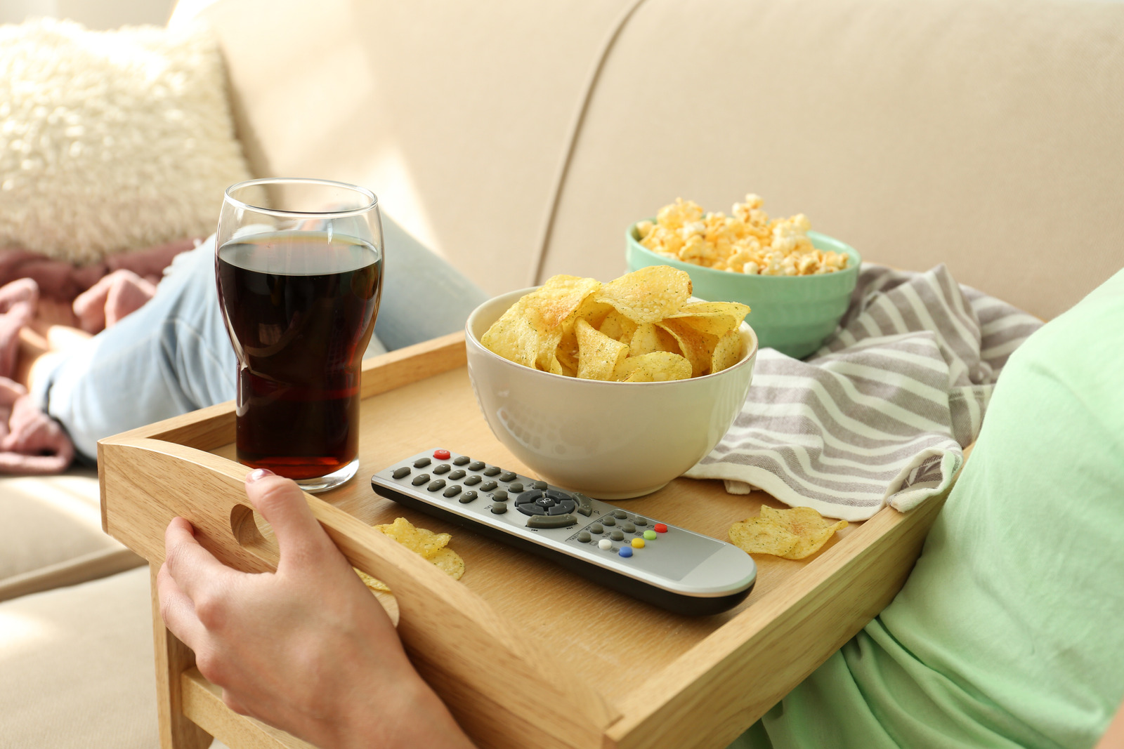 Person With Tray Of Chips And Drink On The Sofa
