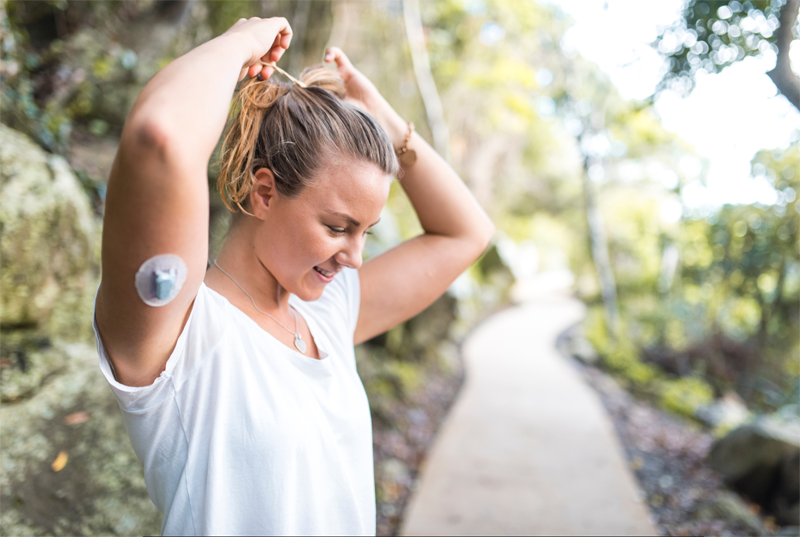 A woman with a CGM on her arm. 
