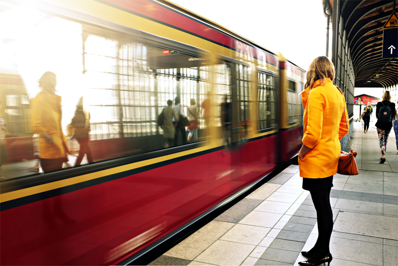 A woman stood by a train on a  railway platform.